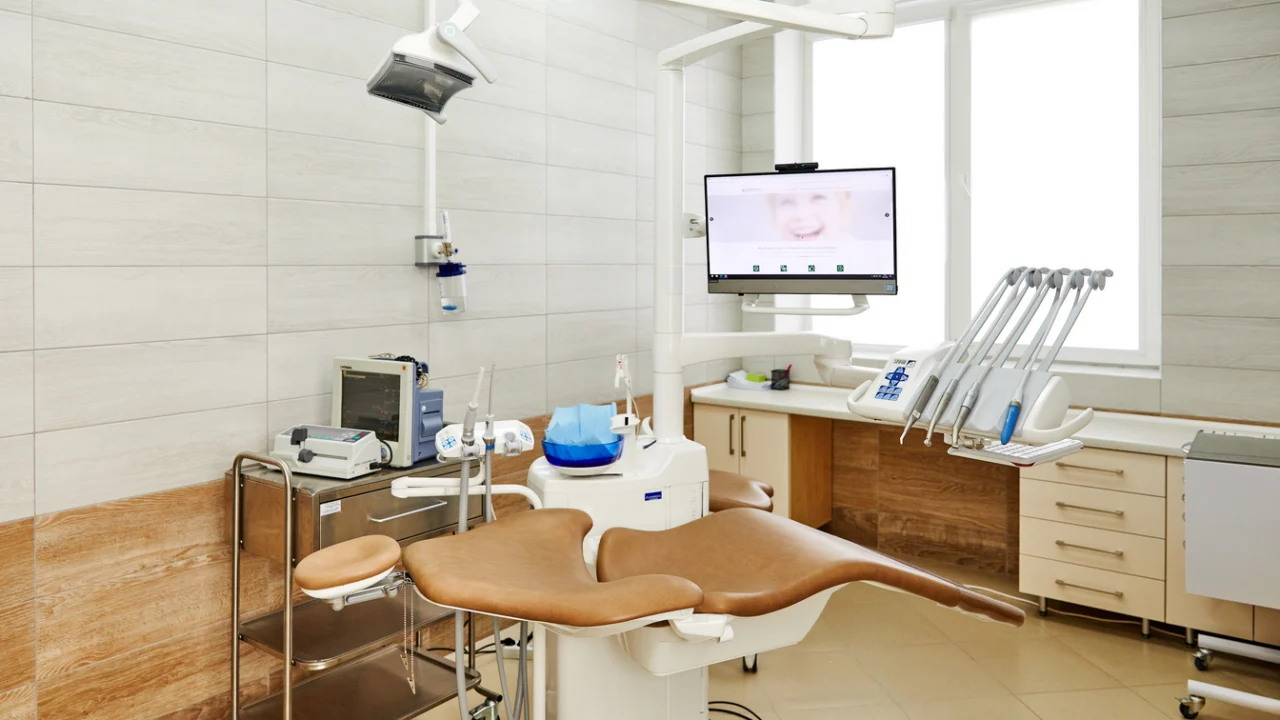 Consultório odontológico com cadeira, refletor e equipamentos em ambiente claro
