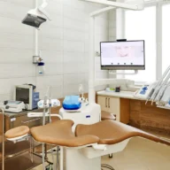 Consultório odontológico com cadeira, refletor e equipamentos em ambiente claro