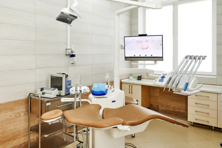 Consultório odontológico com cadeira, refletor e equipamentos em ambiente claro