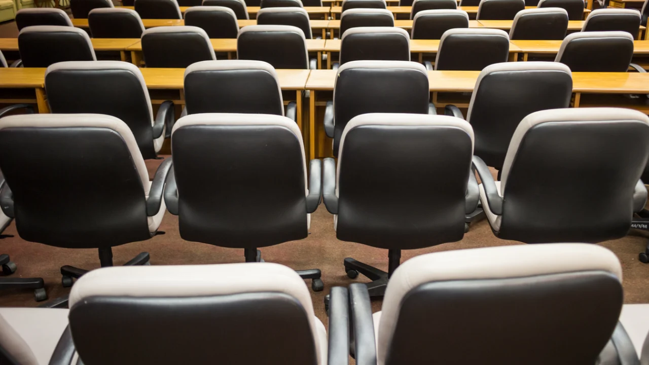 Fileiras de cadeiras em salão de reuniões preparado para palestra