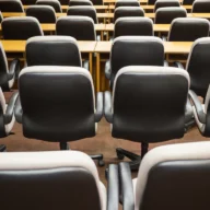 Fileiras de cadeiras em salão de reuniões preparado para palestra