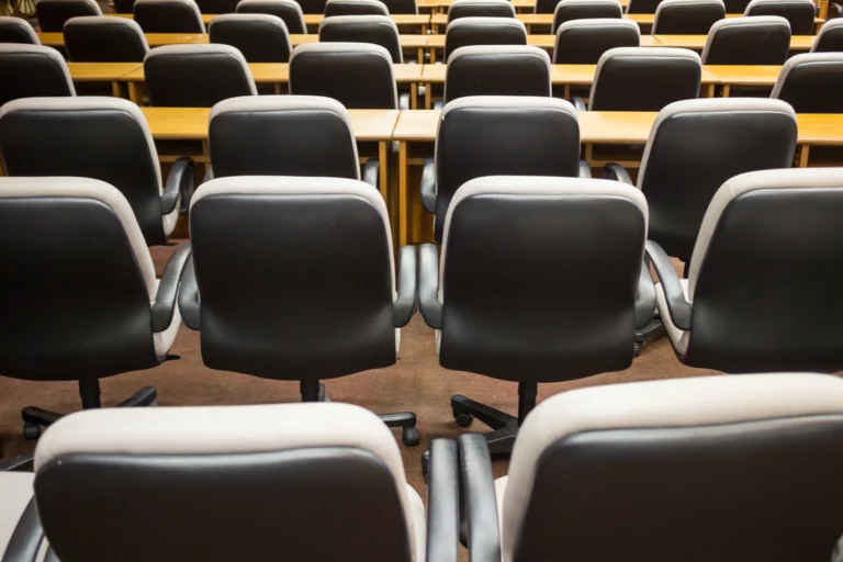 Fileiras de cadeiras em salão de reuniões preparado para palestra