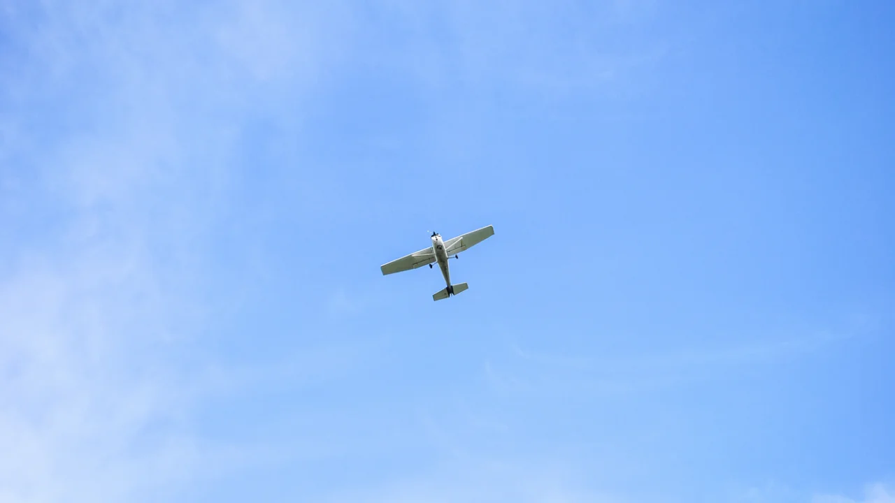 Avião monomotor em voo no céu azul com nuvens claras
