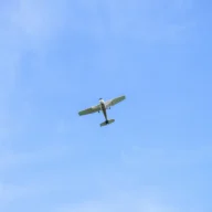 Avião monomotor em voo no céu azul com nuvens claras