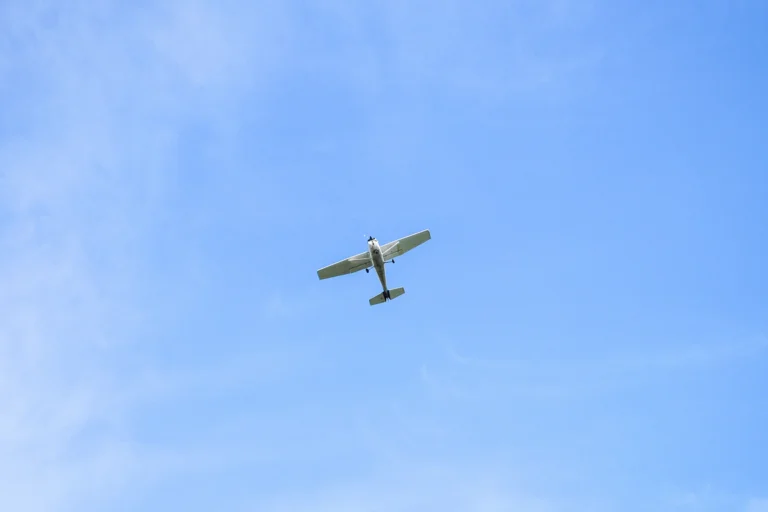 Avião monomotor em voo no céu azul com nuvens claras