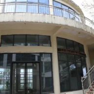 Fachada de um prédio público municipal com escadaria e portas de vidro ao entardecer