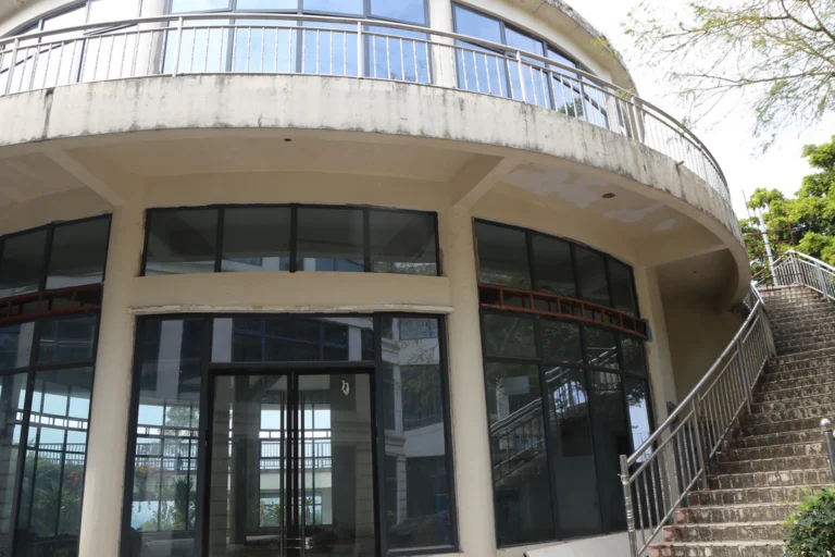 Fachada de um prédio público municipal com escadaria e portas de vidro ao entardecer