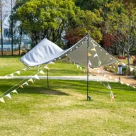 Tendas e bandeirinhas coloridas montadas em uma área verde de parque para evento ao ar livre