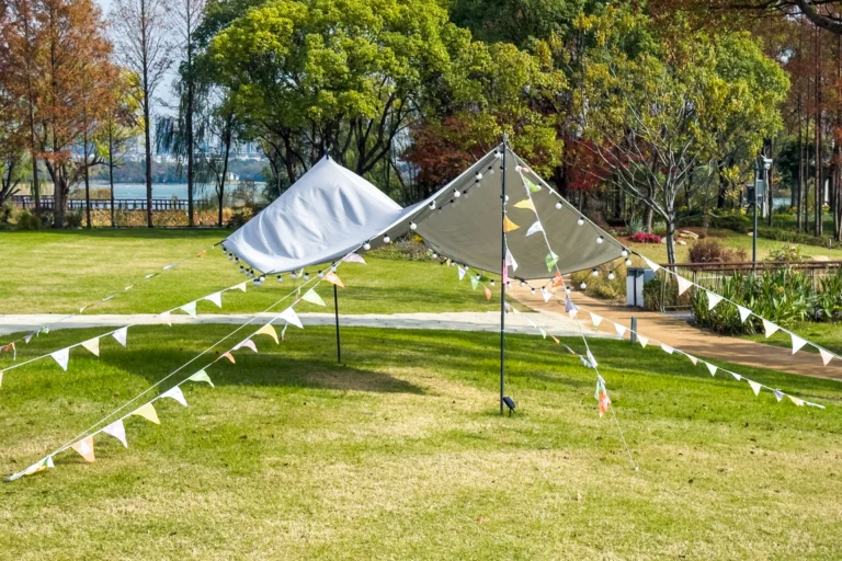 Tendas e bandeirinhas coloridas montadas em uma área verde de parque para evento ao ar livre