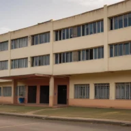 Fachada de prédio escolar de três andares com janelas de vidro, vista da calçada, em manhã de sol