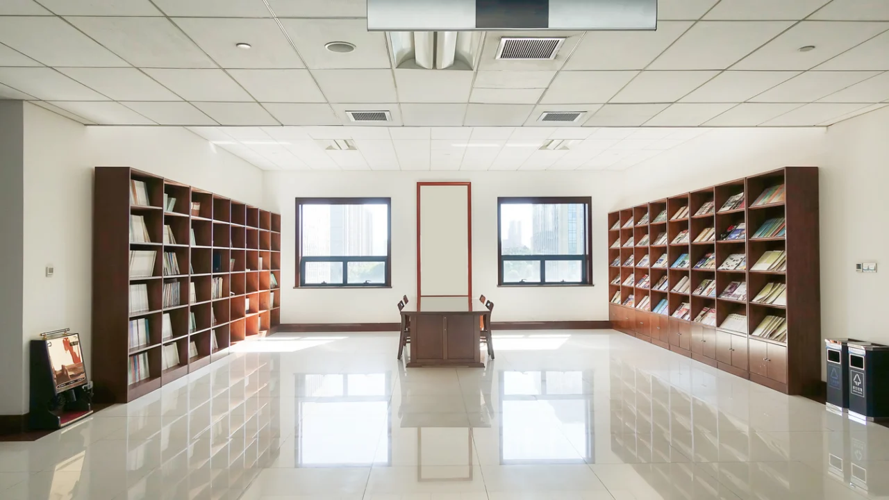 Sala de leitura de biblioteca pública com estantes de livros e mesas de leitura vazias