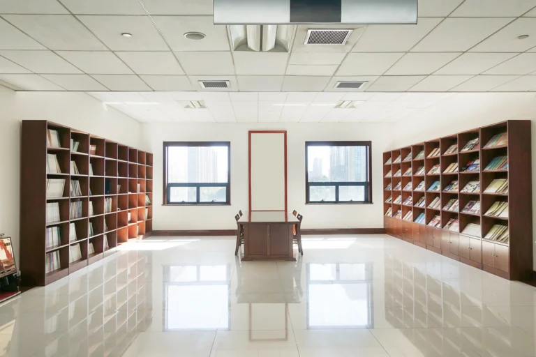 Sala de leitura de biblioteca pública com estantes de livros e mesas de leitura vazias