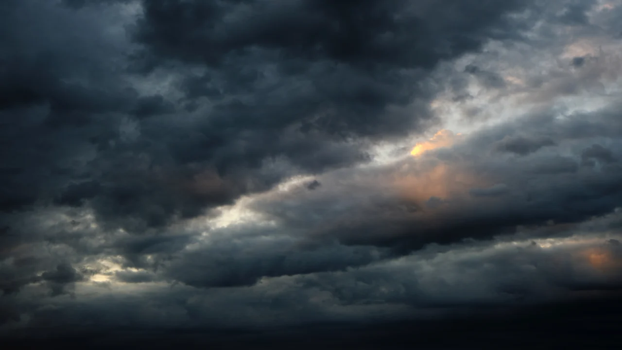 Céu carregado de nuvens escuras de tempestade, com frestas de luz do fim da tarde
