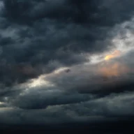 Céu carregado de nuvens escuras de tempestade, com frestas de luz do fim da tarde