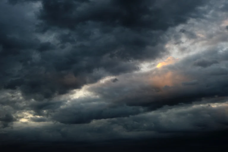 Céu carregado de nuvens escuras de tempestade, com frestas de luz do fim da tarde