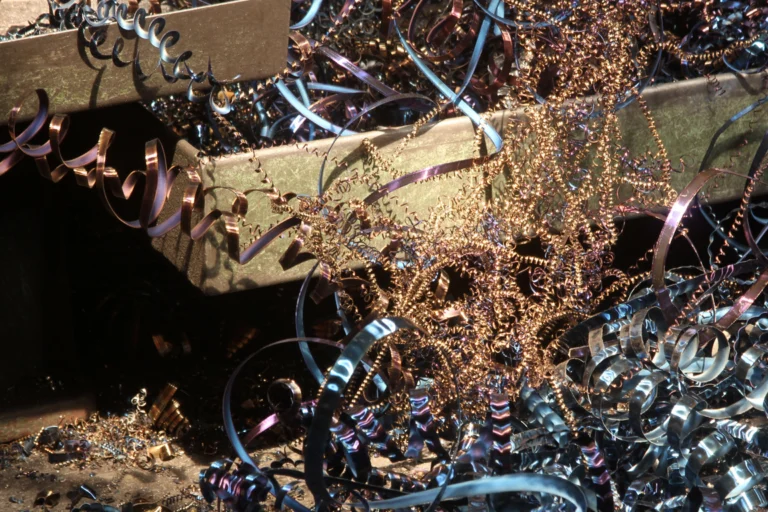 Aparas e fitas de cobre e metal acumuladas em pátio de reciclagem sob luz do dia