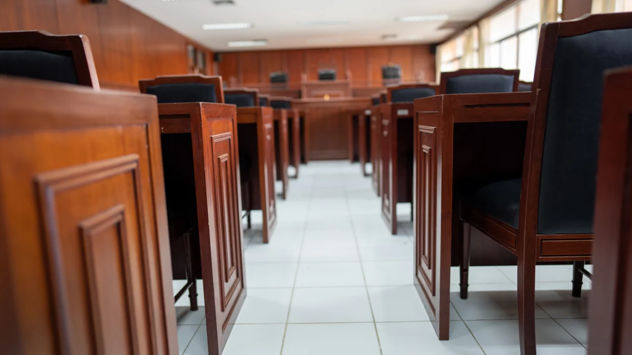 Sala de audiência com bancos e cadeiras de madeira enfileirados em um corredor central