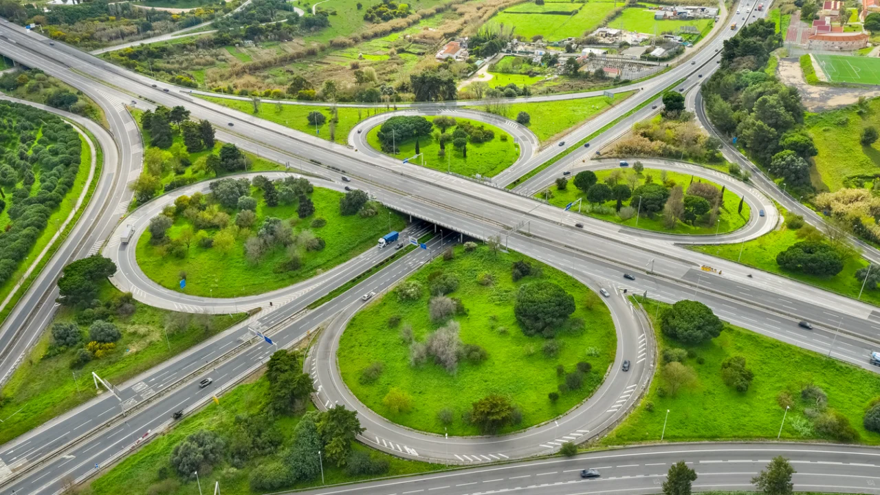 Trevo rodoviário em formato de folha de trevo visto de cima, com faixas de rolamento e áreas verdes ao redor